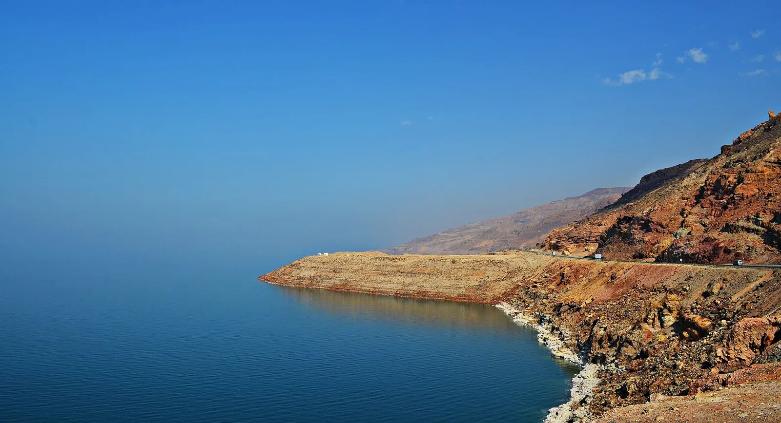 Blue water and salt-crusted shore of the Dead Sea from the Jordanian side